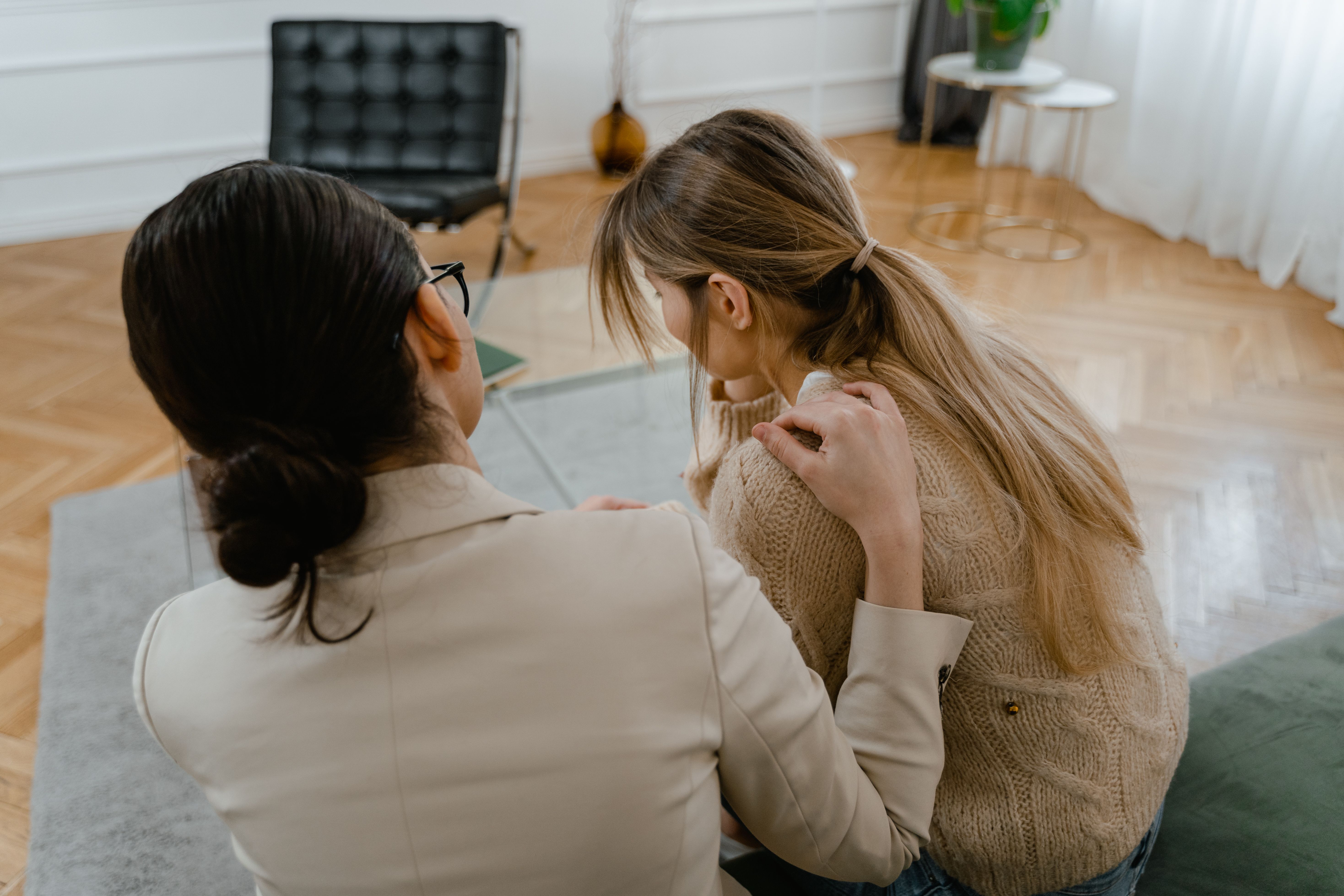 Two women sharing a moment of emotional support and empathy, sitting closely together indoors