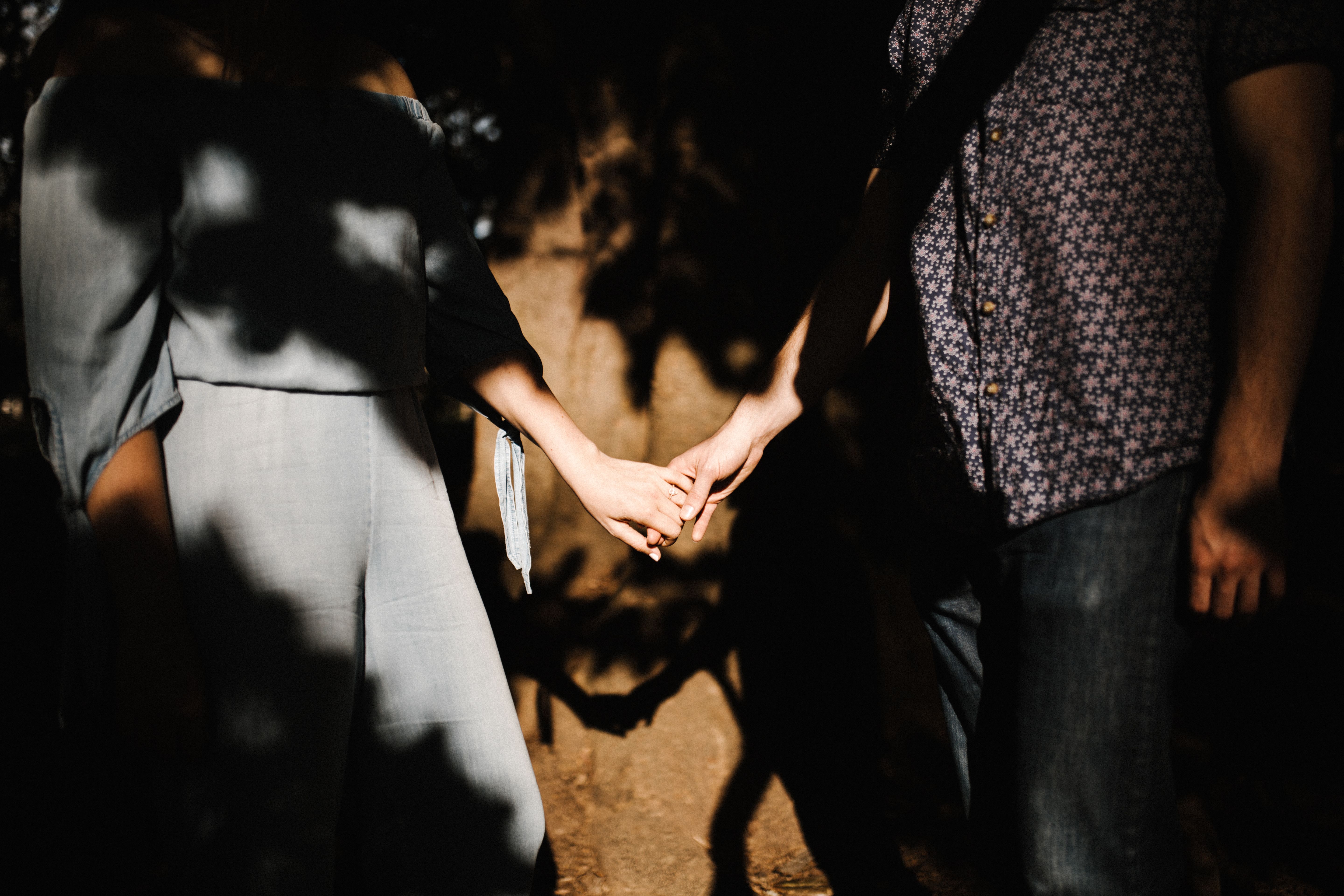 Romantic couple holding hands with intimate shadows and sunlight outdoors, symbolizing trust and closeness