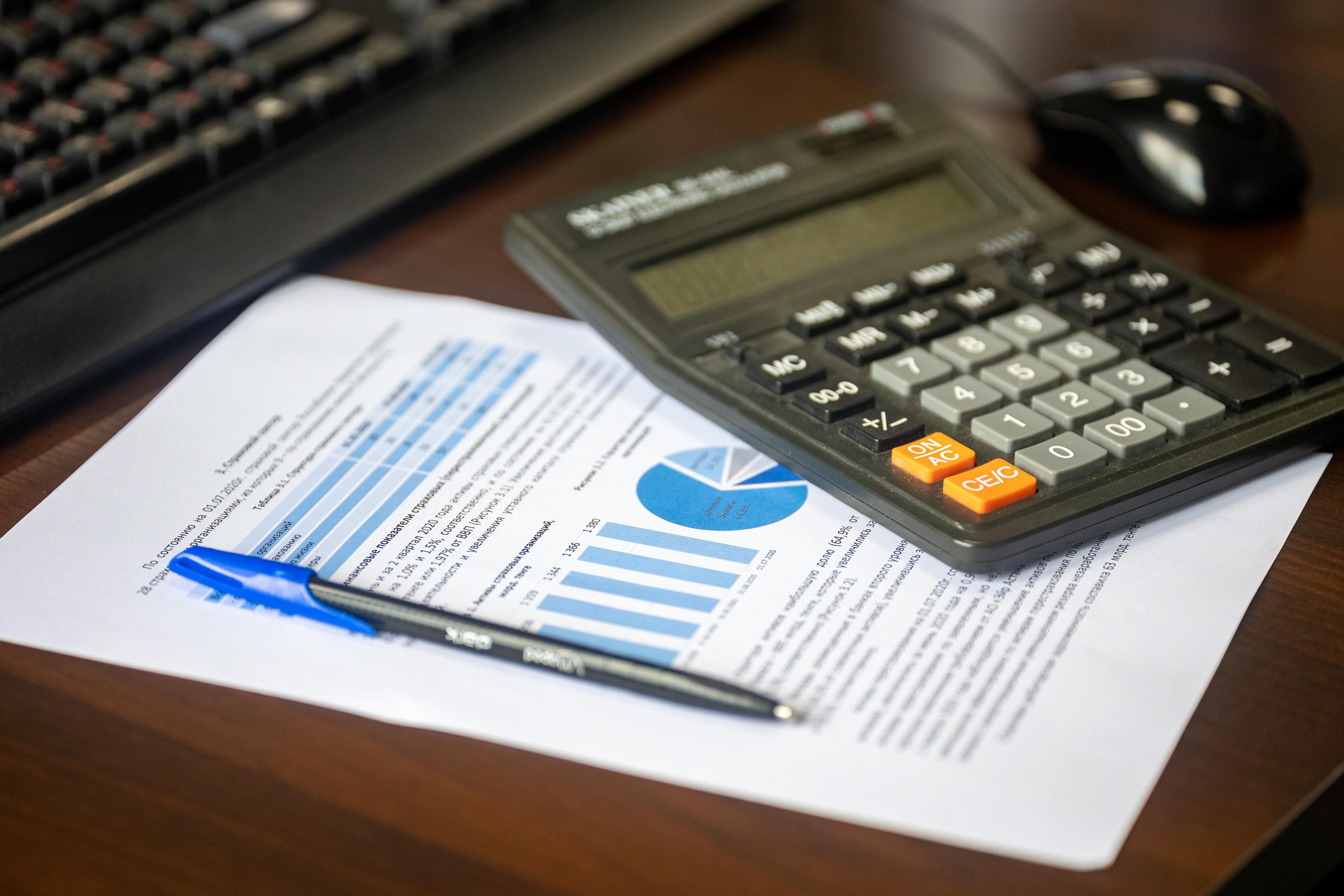 Desk with calculator, financial report and pen for legal case budget analysis