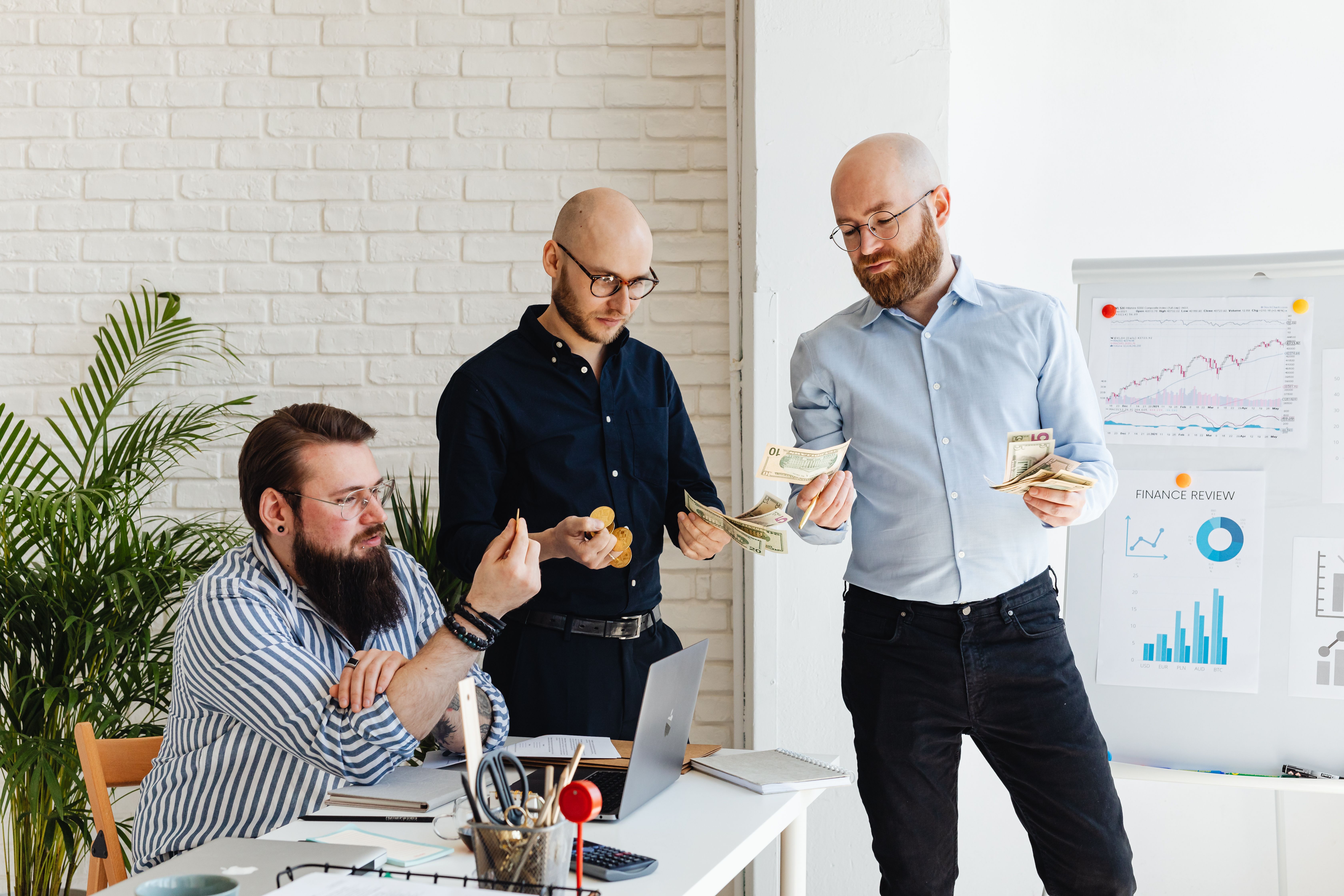 Three business colleagues discussing financial strategies and reviewing charts in a modern office